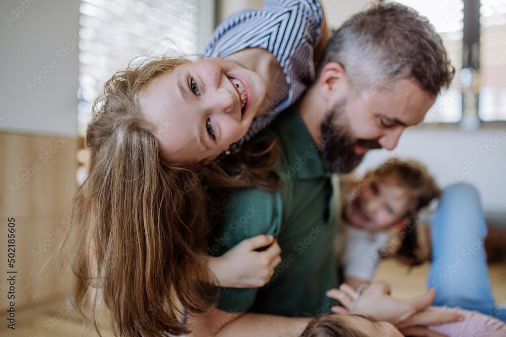 Cheerful father with three little daughters playing together at home