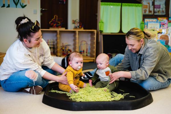 Two adults and two babies doing sensory play