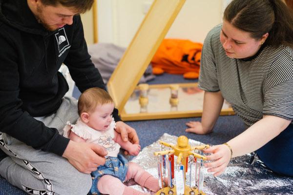 Two adults playing with a baby